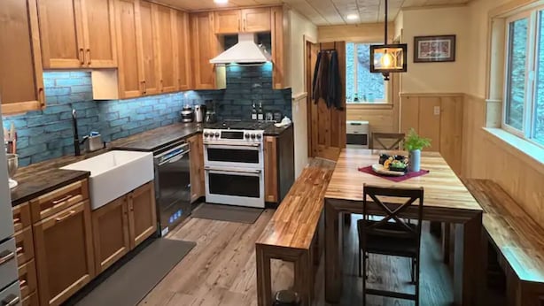 A kitchen with wooden cabinets, a stove, and a sink. - Oz Lodge: Tiehacker Chalet.

 (Seward)