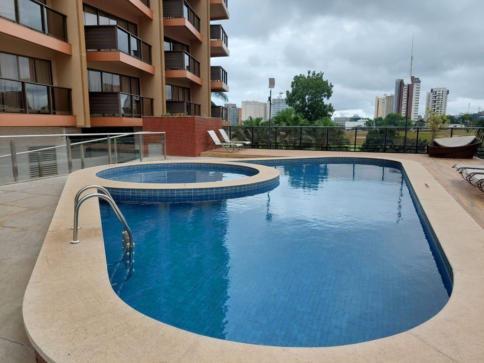 A rectangular swimming pool with a tiled edge, surrounded by a beige deck.