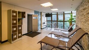 Une salle d’attente comprenant un comptoir d’accueil, des sièges, un téléviseur et une grande fenêtre donnant sur un espace verdoyant.