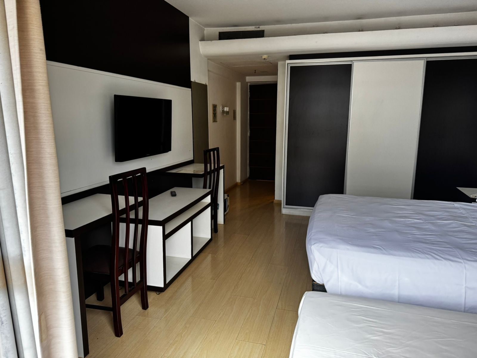 A hotel room with a bed, a desk with a TV, and a sliding door closet.