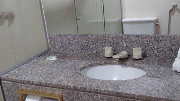A bathroom with a granite countertop, a sink, a toilet, and a mirror.