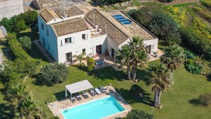 A two-story house with a swimming pool, surrounded by lush greenery and palm trees. - Villa Casale-Villa in Sicily with pool and sea views (Arcieri - Isolotto)