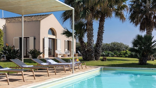 A pool area with lounge chairs, a covered seating area, and palm trees. - Villa Casale-Villa in Sicily with pool and sea views (Arcieri - Isolotto)