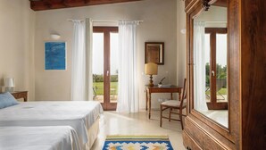 A bedroom with two beds, a wooden cabinet, a desk with a lamp, and a view of the outdoors. - Villa Casale-Villa in Sicily with pool and sea views (Arcieri - Isolotto)