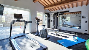 Un gimnasio con cintas de correr, bicicletas estáticas y un espejo.