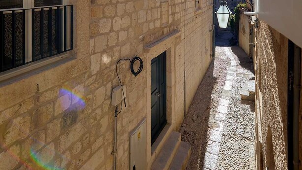 A narrow alleyway with stone buildings, a small door, and a window with a black railing. - Dominium Premium Location Suites Studio apartment (Dubrovnik)