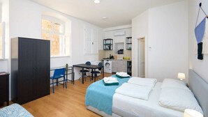A compact bedroom with a bed, a desk, and a washing machine. - Dominium Premium Location Suites Studio apartment (Dubrovnik)
