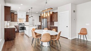 Una cocina moderna con armarios de madera, una isla central y un comedor con sillas.