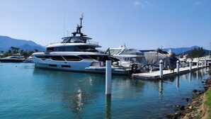 A marina with a large yacht docked at a pier, surrounded by calm water and mountains in the background. - Angra Temporada (Angra dos Reis)
