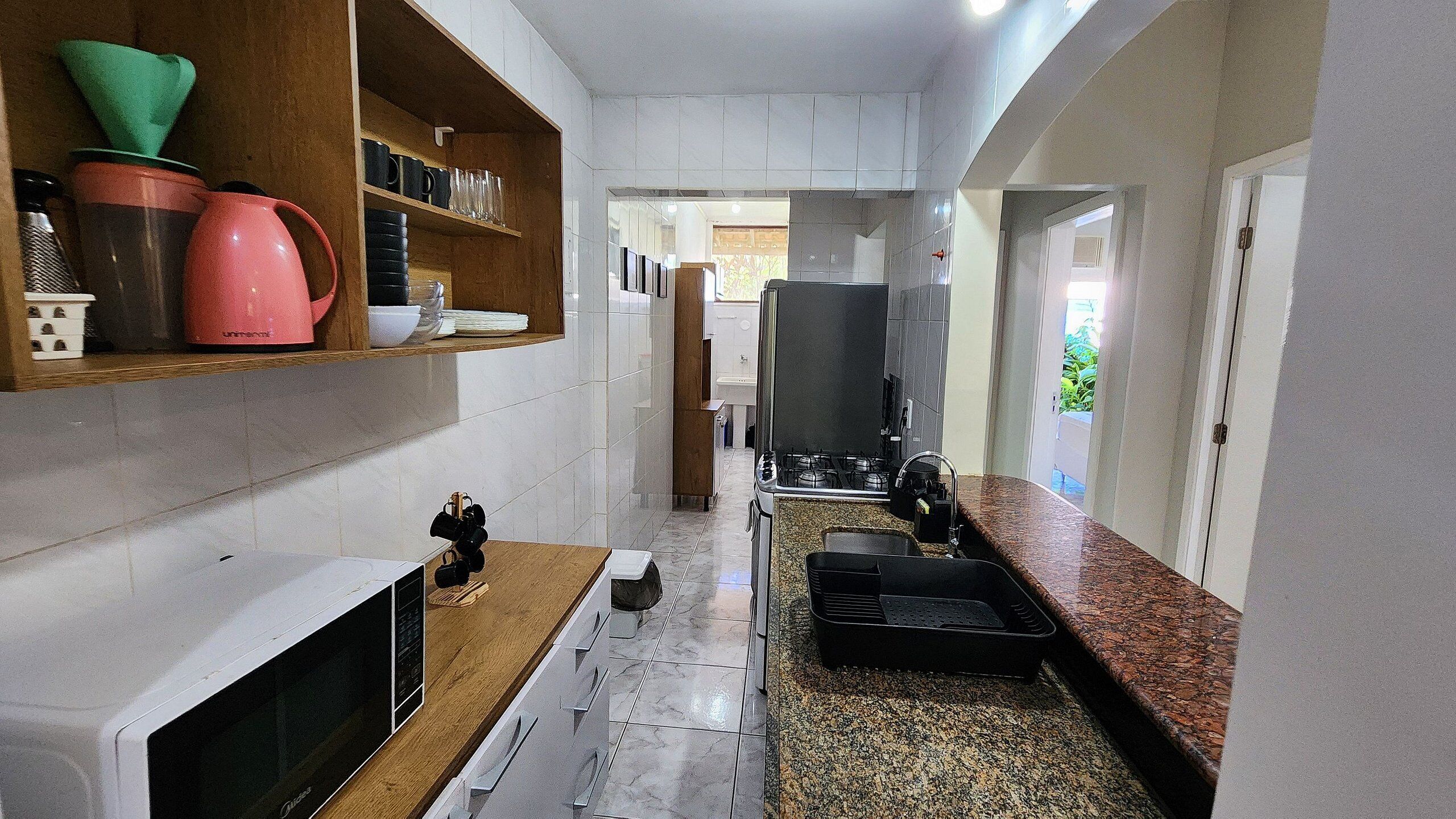 Una cocina estrecha con microondas, estufa y diversos utensilios de cocina.