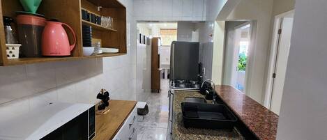 Una cocina estrecha con microondas, estufa y diversos utensilios de cocina.