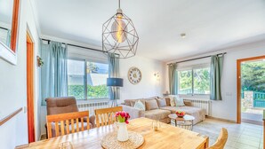 A modern living room with a wooden dining table, a sofa, and a large window. - House with pool Casa Kerchner in Alcudia (Alcúdia)