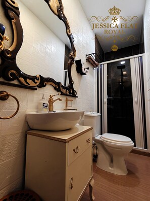 Un baño con un espejo grande, un lavabo con recipiente, inodoro y zona de ducha.
