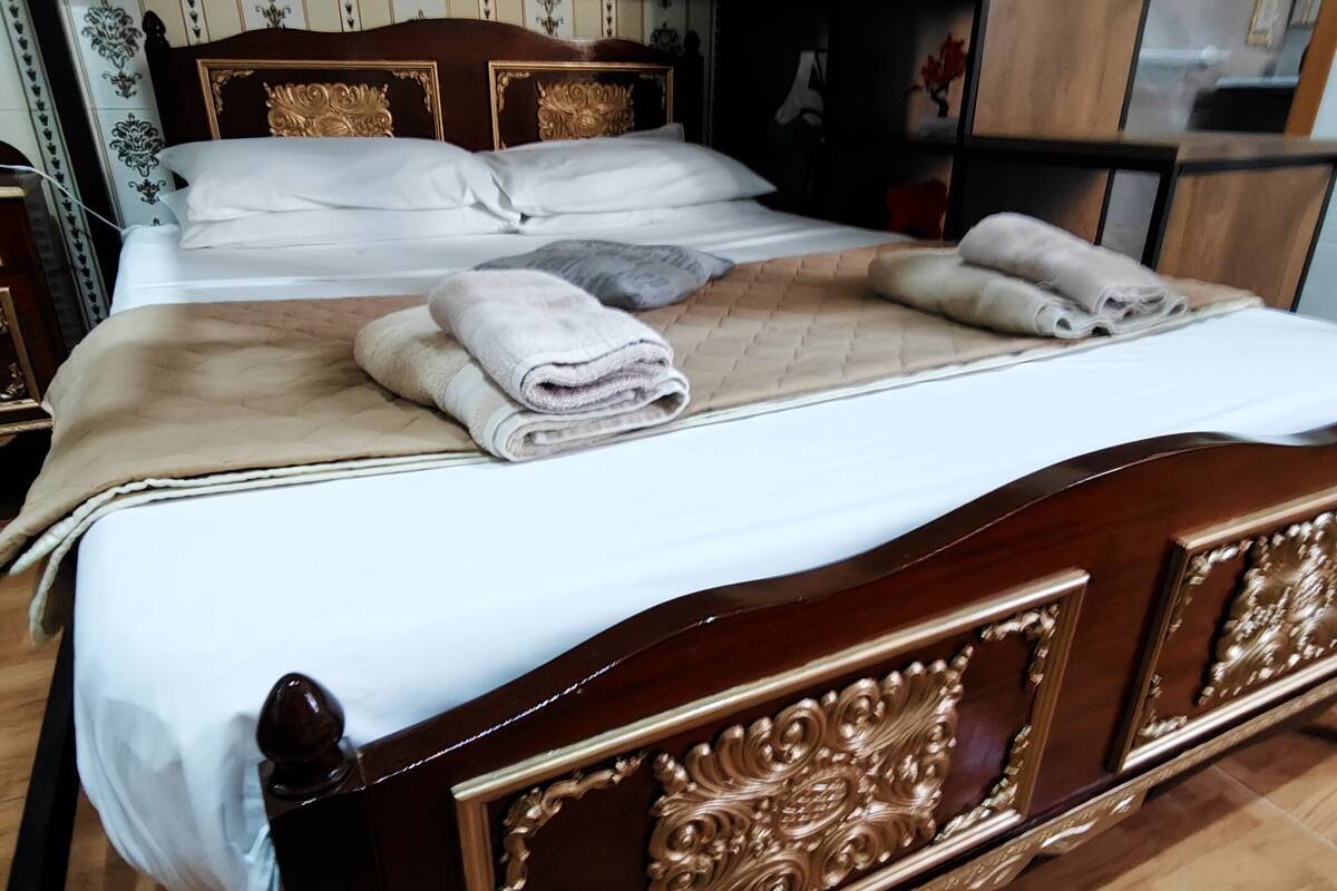 A wooden bed with a headboard, a wardrobe, and a mirror.