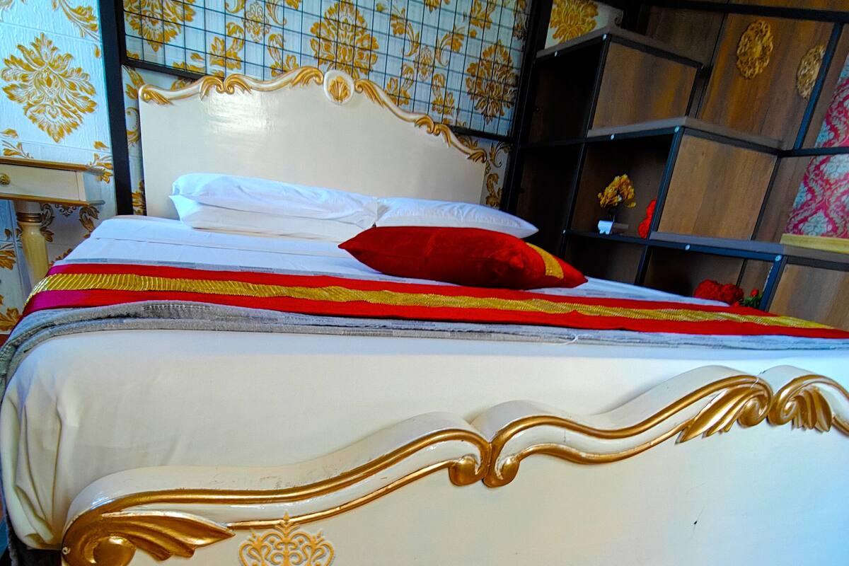 A bed with a white headboard and footboard, adorned with gold trim and the name "JESSICA FLAT ROYAL" embroidered on the footboard.
