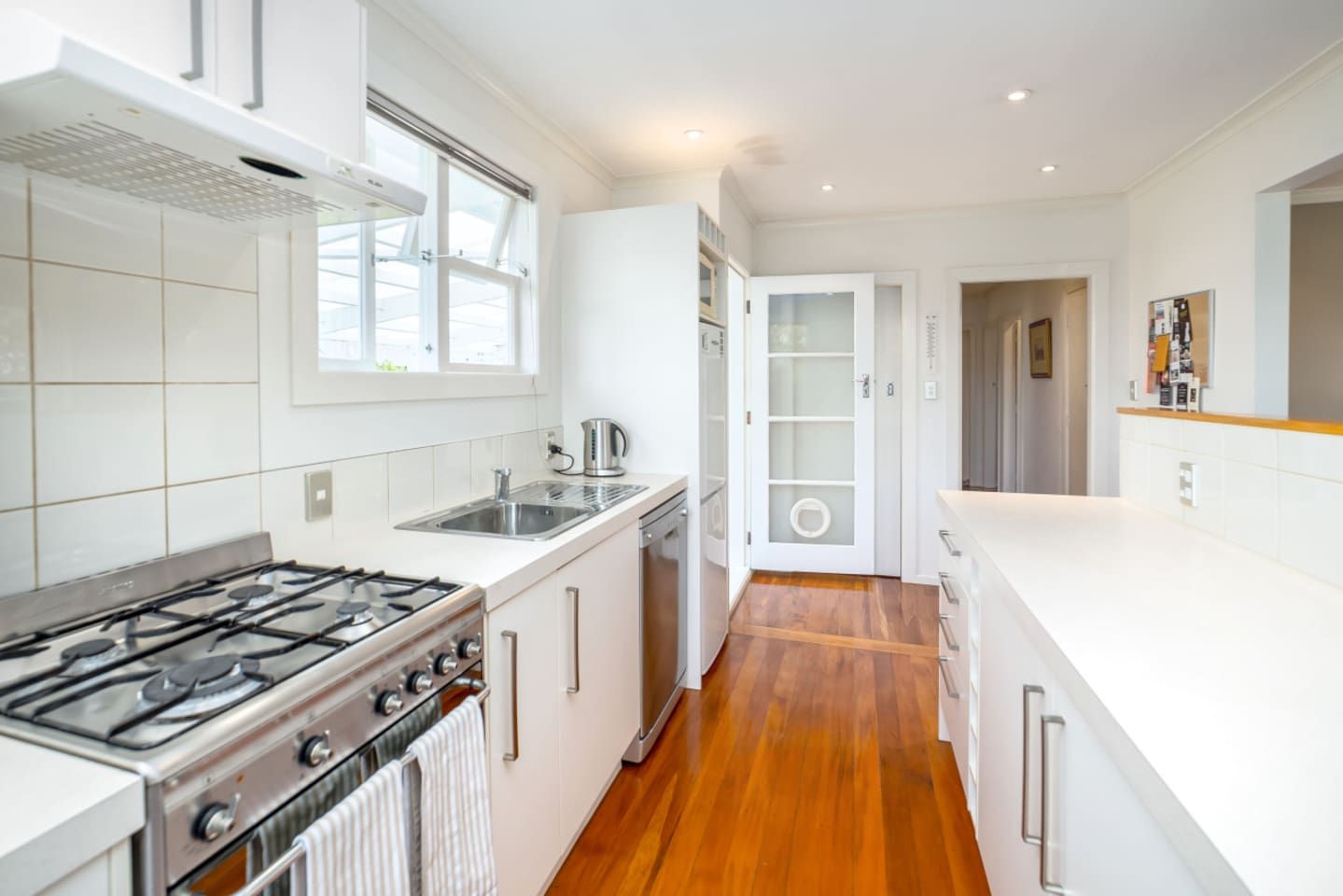 Una cocina moderna con estufa a gas, electrodomésticos de acero inoxidable y piso de madera.