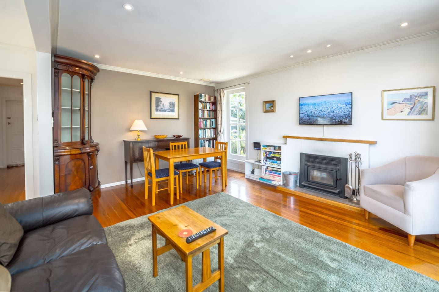 Una sala de estar con chimenea, un sofá, una mesa de comedor y una estantería.