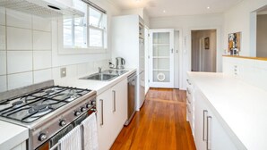 Una cocina moderna con armarios blancos, estufa a gas, lavavajillas y una ventana que proporciona luz natural.