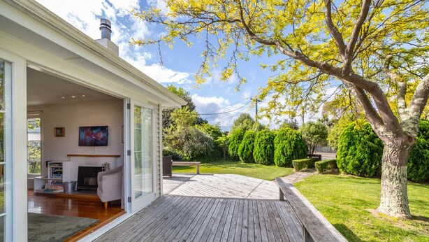 Una casa moderna con terraza de madera, chimenea y jardín cuidado.