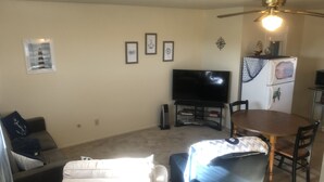A living room with a flat-screen TV, a dining table, and a ceiling fan. - Cozy nautical-themed studio with private entrance (San Diego)