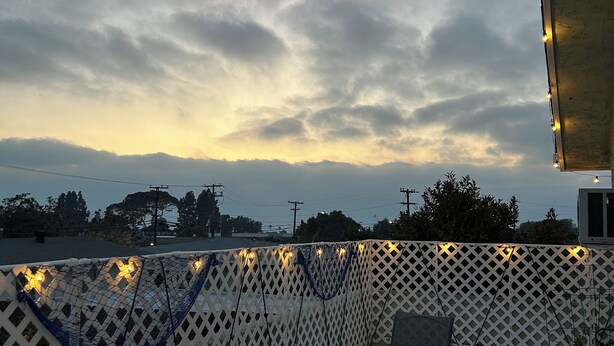 An outdoor patio with a table and chairs, a white lattice fence, and string lights. - Cozy nautical-themed studio with private entrance (San Diego)