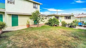 A two-story residential building with a green door, a small tree, and potted plants. - Cozy nautical-themed studio with private entrance (San Diego)