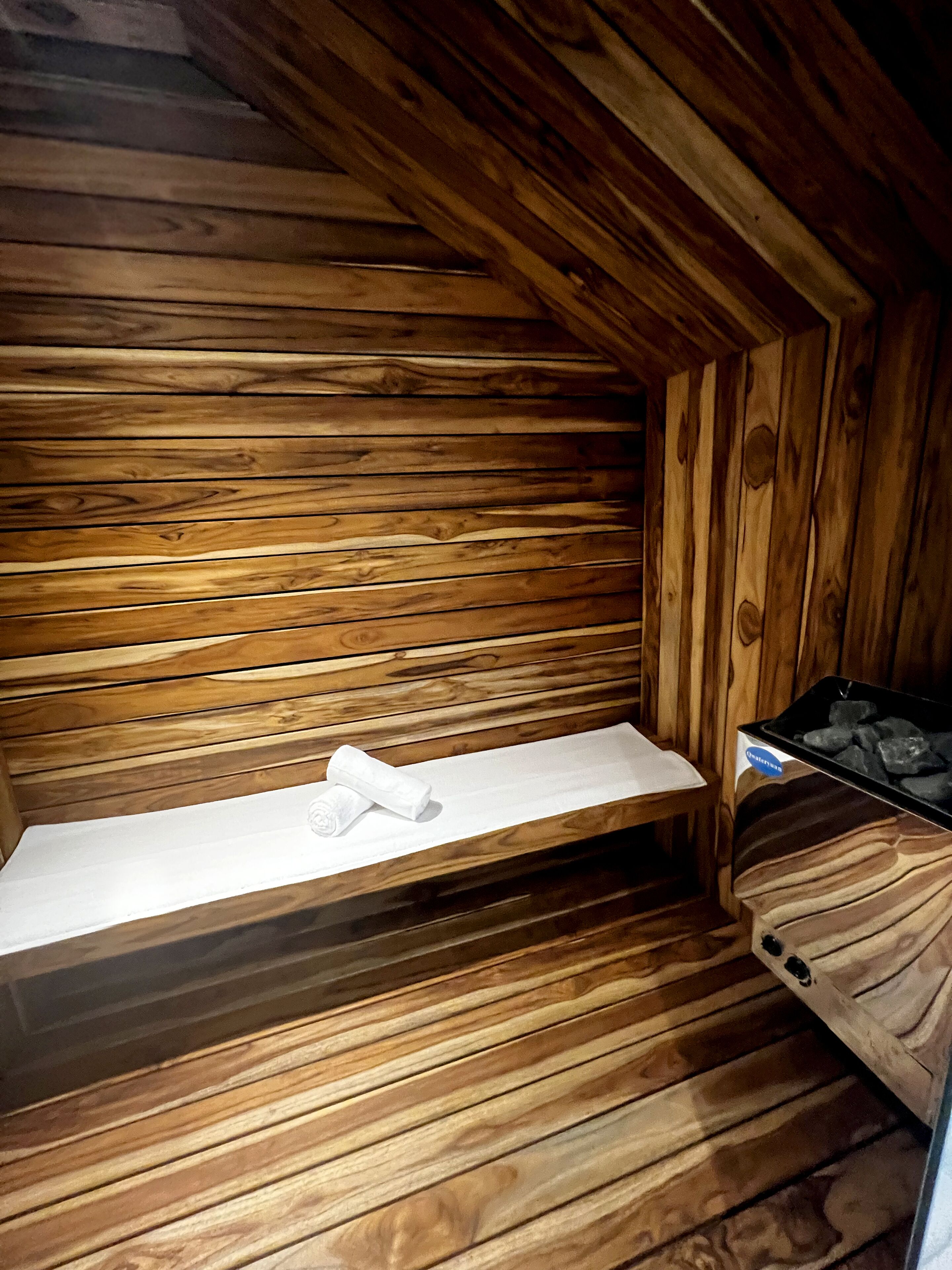 Ein Holzblockhaus-Innenraum mit einer Bank, einem Regal mit Handtuch und einem Heizgerät.