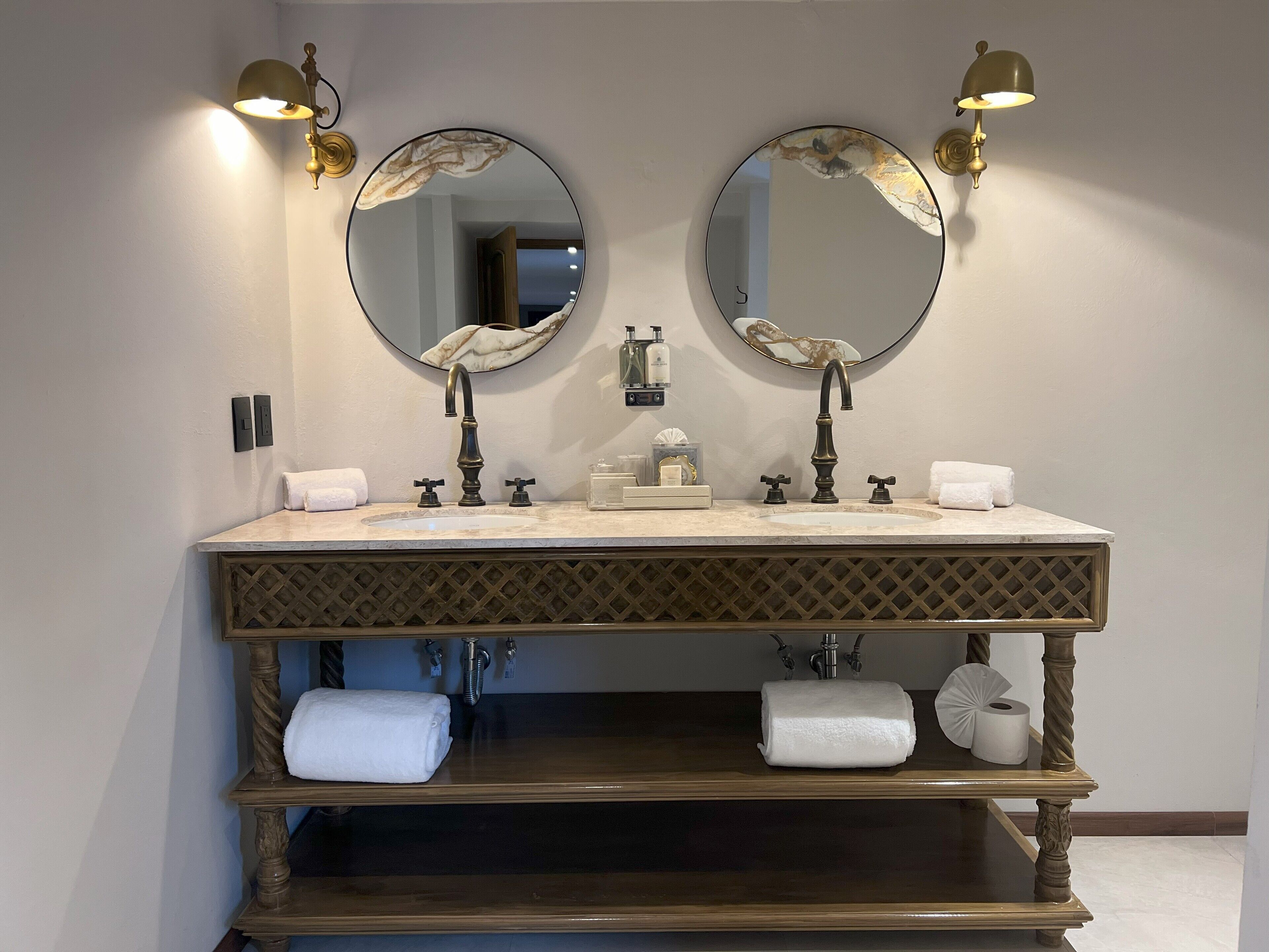 A bathroom with a double sink, two wall-mounted mirrors, and a vanity with a wooden base.