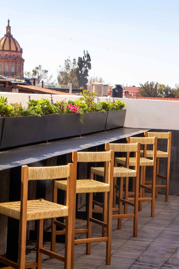 Outdoor seating with woven chairs and a planter with flowers.