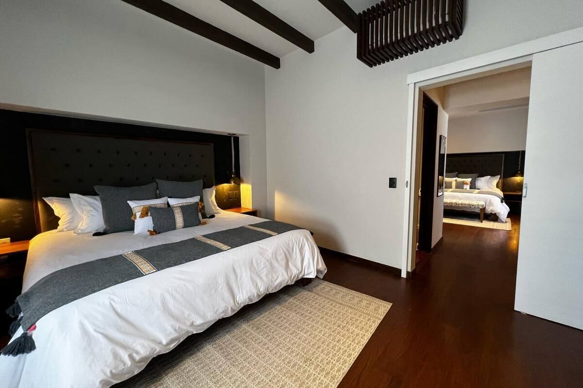 Ein modernes Schlafzimmer mit einem großen Bett, einer Kopfteil und einem Nachttisch mit Lampe.
