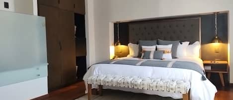 Un dormitorio con una cama grande, un armario de madera y dos lámparas de noche.