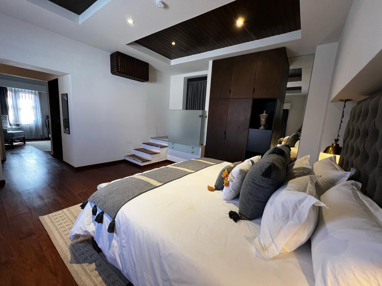 Un dormitorio moderno con una cama grande, techo de madera y una escalera que lleva a un nivel superior.