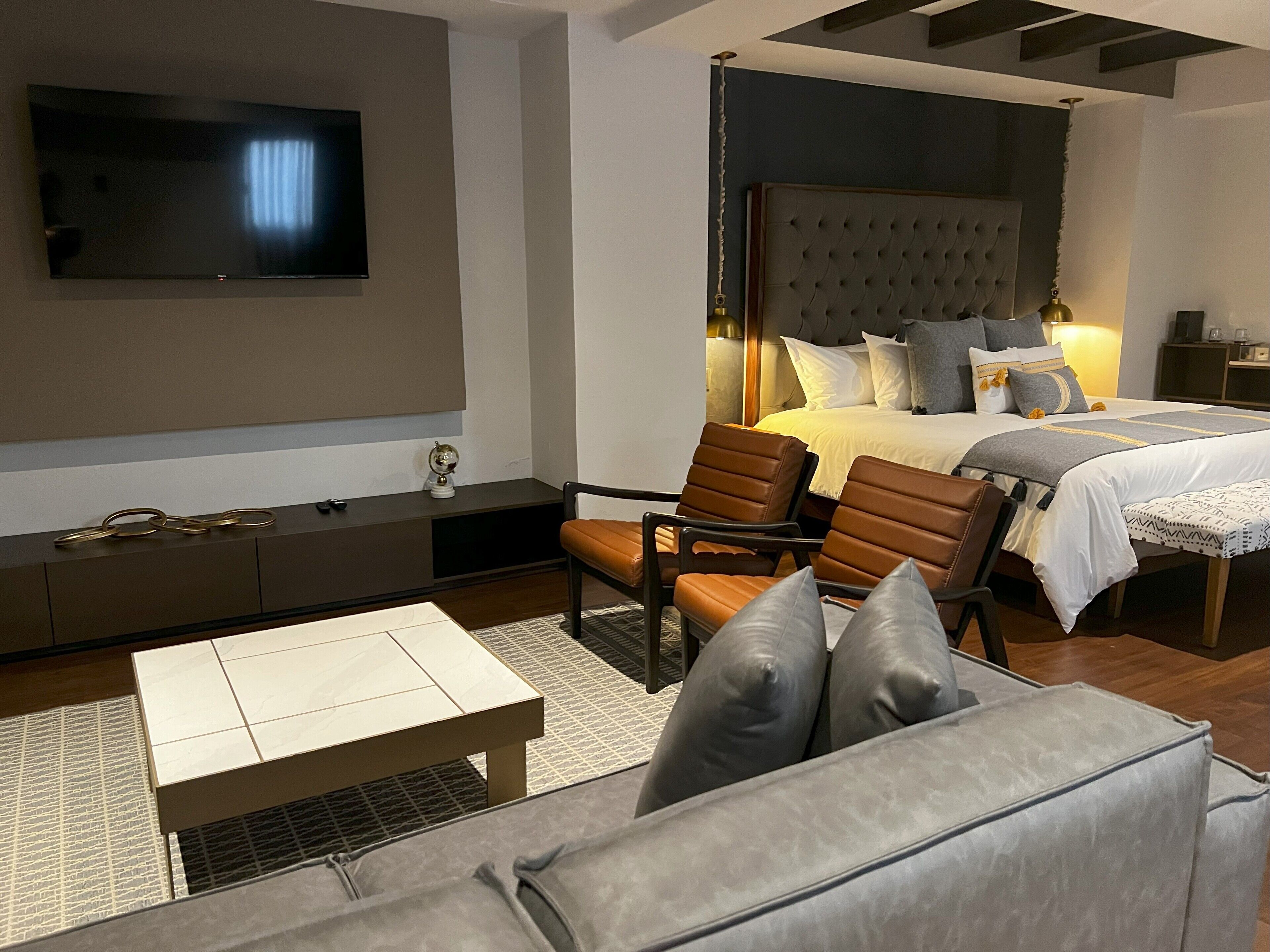 Ein modernes Hotelzimmer mit einem großen Bett, einem Flachbildfernseher, einer Sitzecke mit Couchtisch und einer Couch.