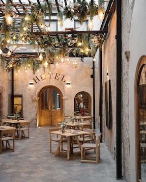 An indoor dining area with wooden tables and chairs, a stone floor, and a sign that reads "HOTEL".