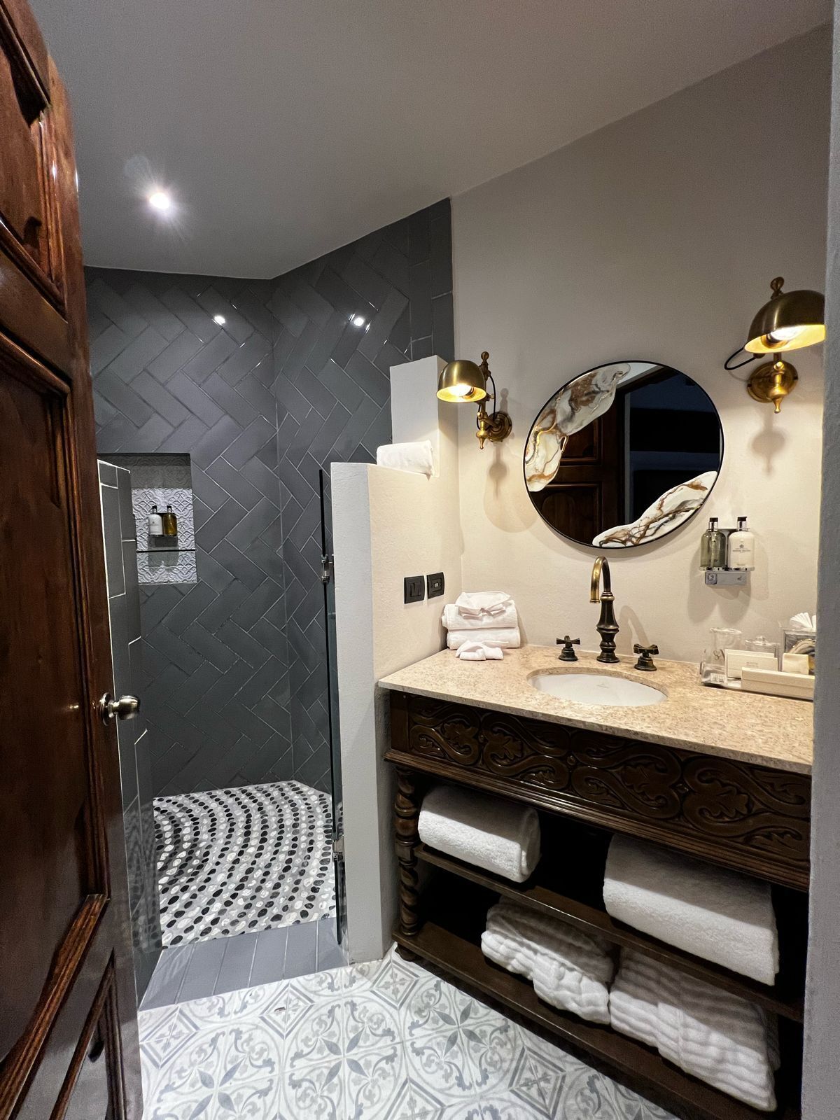 Une salle de bain moderne avec un grand miroir, deux lavabos et un espace douche.