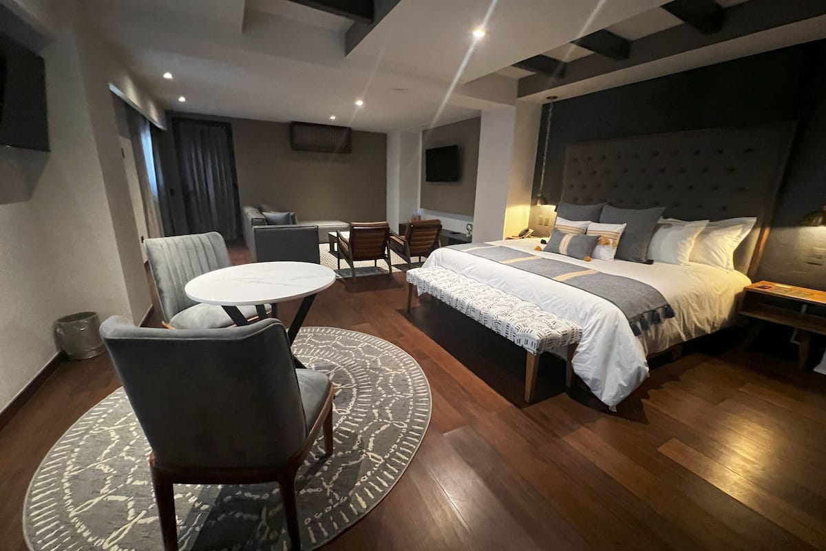 Ein modernes Hotelzimmer mit einem großen Bett, einem Esstisch und einer Couch.