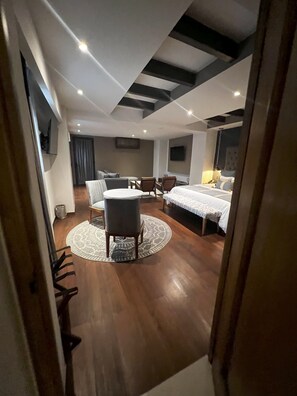 A hotel room with a bed, a desk, a chair, a TV, and a round rug.