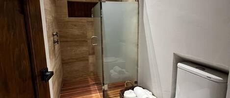 Un baño con puerta de madera, cabina de ducha de vidrio, inodoro y bidé.