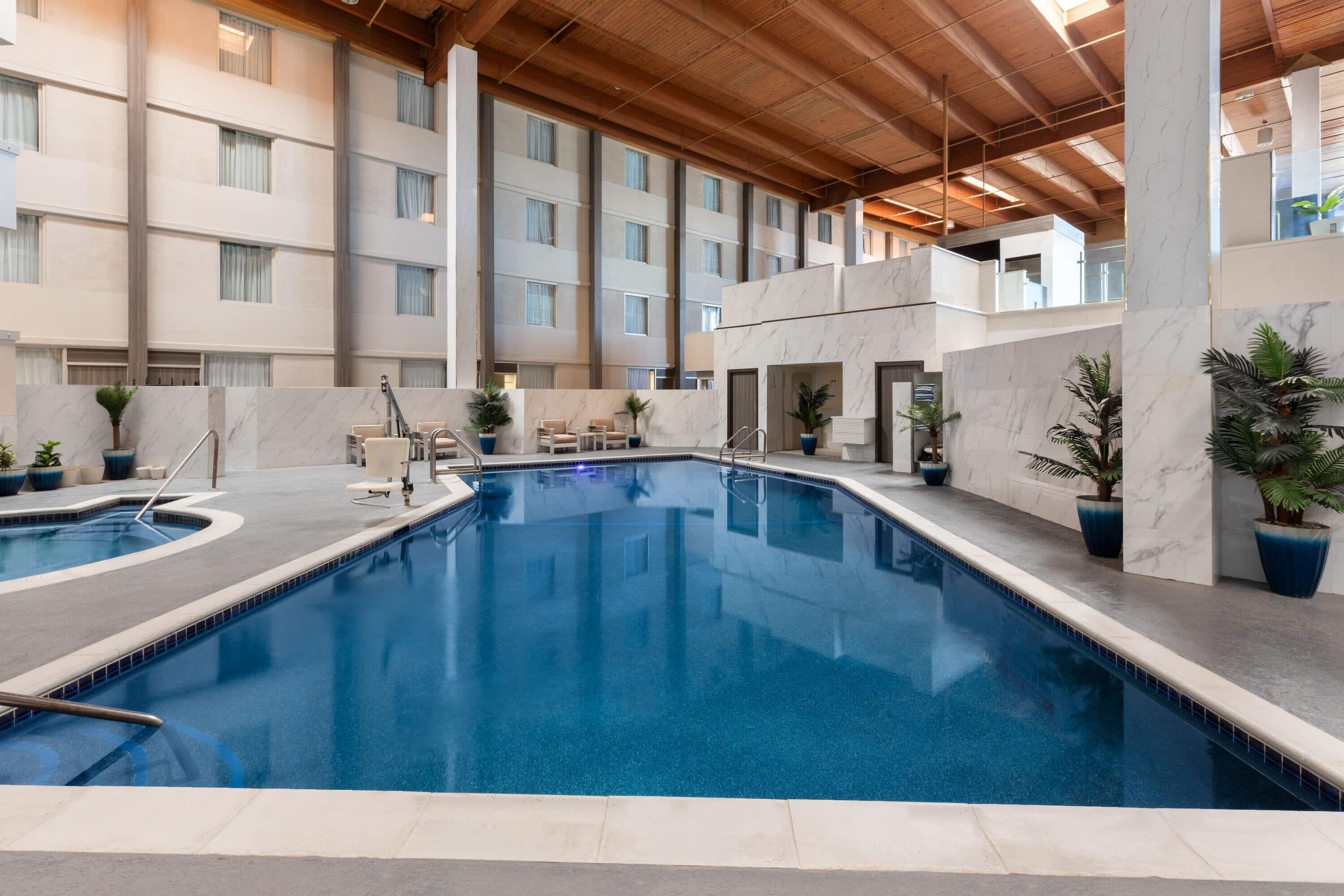 Alberca techada, alberca al aire libre y sombrillas en la alberca