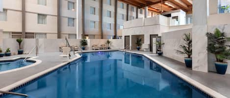 Alberca techada, alberca al aire libre y sombrillas en la alberca