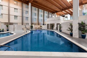 Una piscina techada, una piscina al aire libre, sombrillas