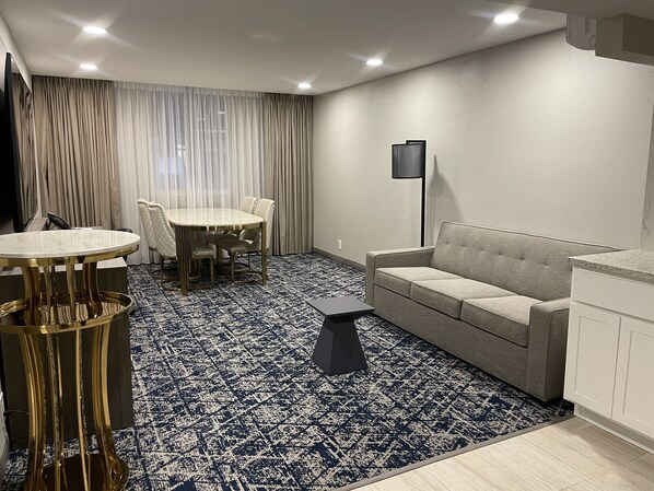 Una sala de estar moderna con una mesa redonda, sofá y alfombra estampada.