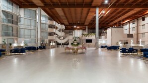 A spacious lobby with a high ceiling, multiple seating areas, and a central decorative table. - Wyndham DFW Airport (Irving)