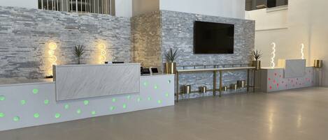 Una moderna zona de recepción con una pared de piedra, un televisor de pantalla plana y un mostrador con encimera de cristal.