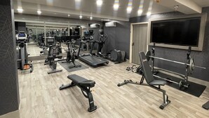 A gym with various exercise equipment, a bench, and a TV on the wall. - Wyndham DFW Airport (Irving)