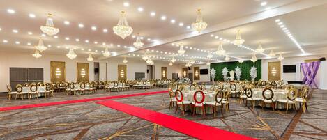 Une salle de banquet avec des tables rondes, des chaises dorées et des lustres.