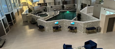 A spacious indoor pool area with multiple seating arrangements and a central pool.