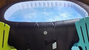 Ein Whirlpool mit Holzverkleidung, einer kleinen Trepille und zwei Stühlen.