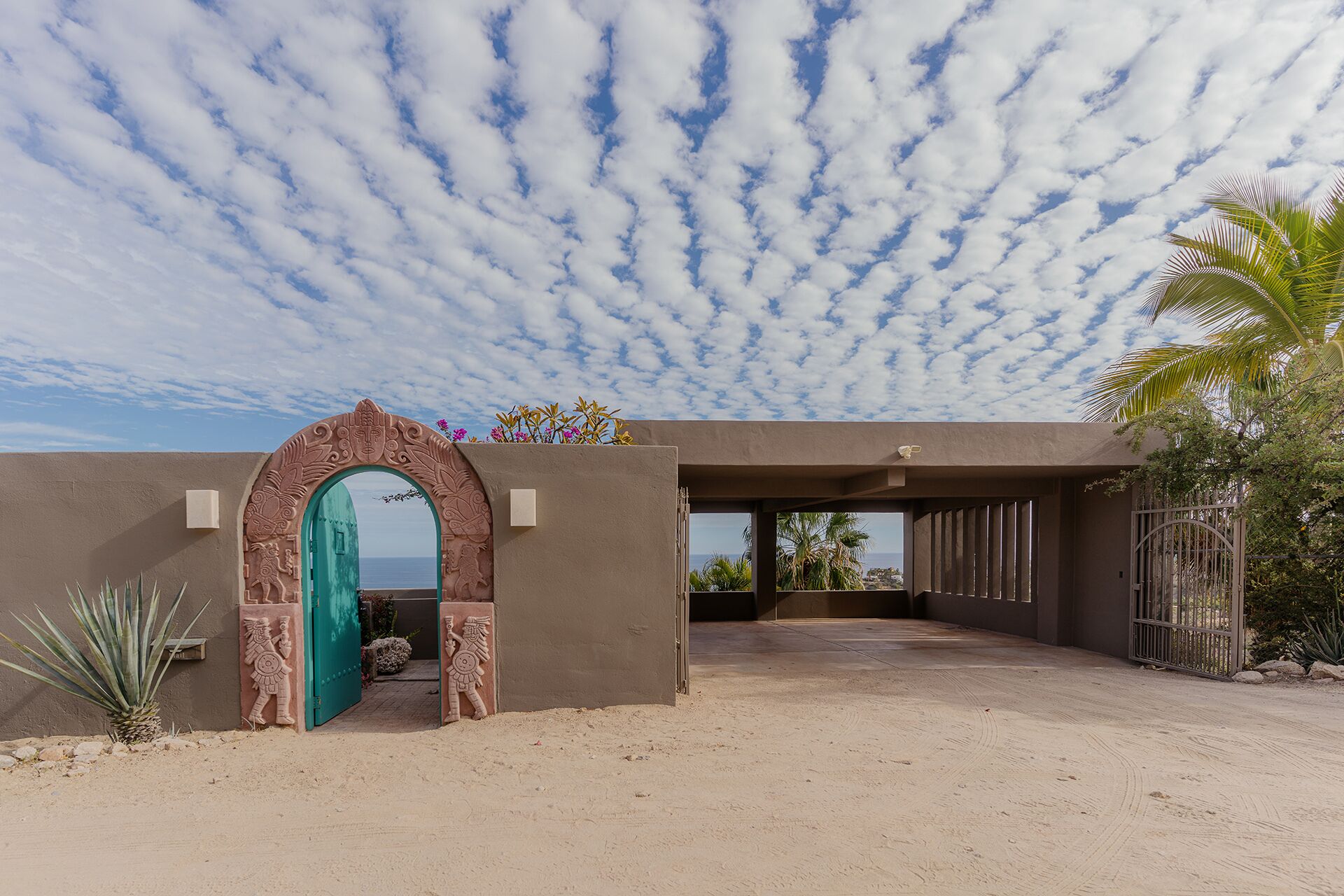 A modern building with a large arched entrance, a view of the ocean, and a desert landscape.