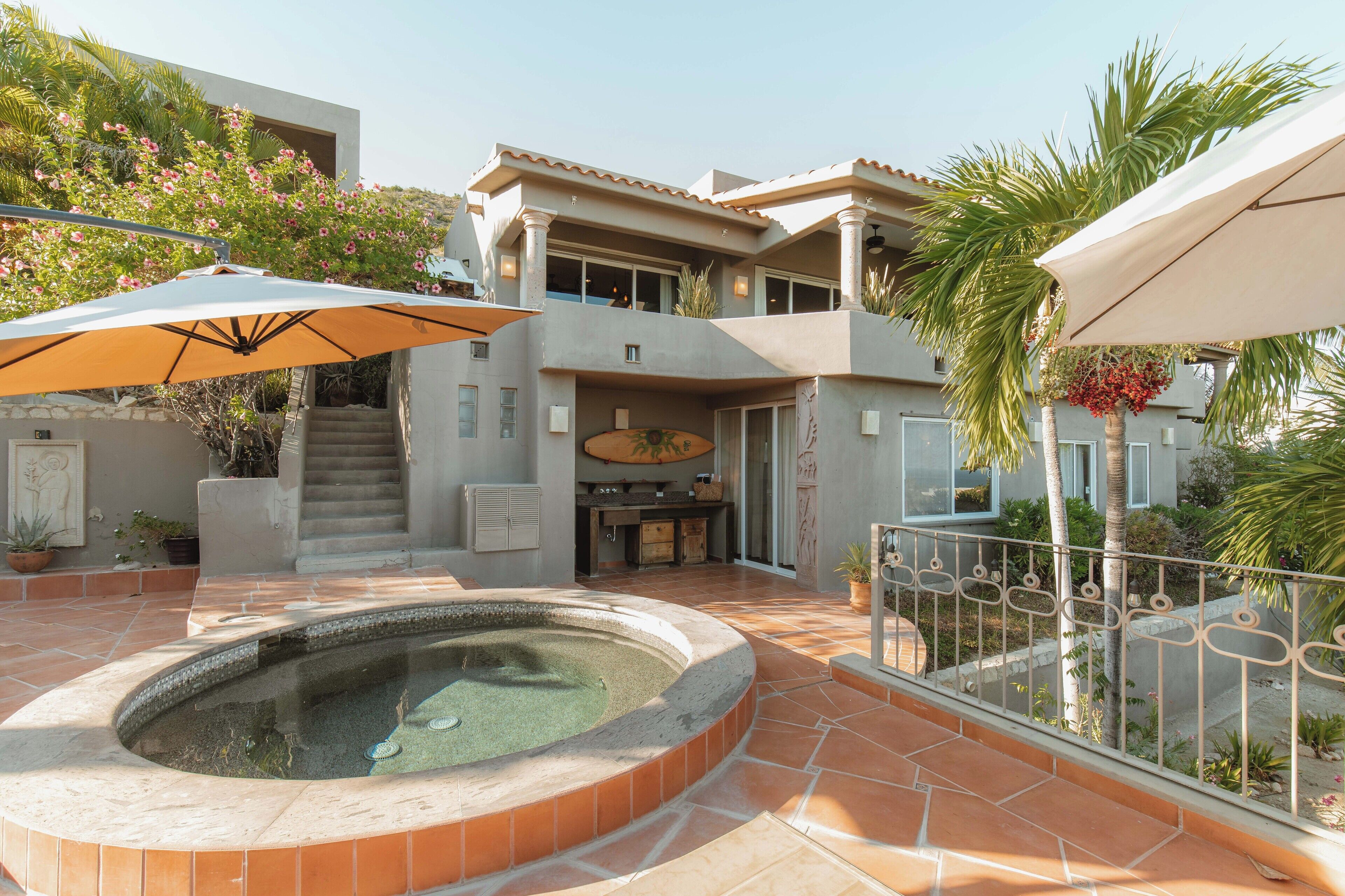 Una casa moderna con piscina, zona de estar exterior y una escalera que conduce a la planta superior.